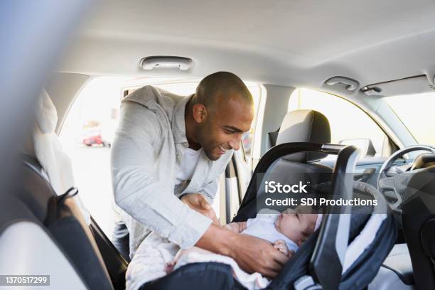 New Dad Puts Baby Girl In Safety Seat In Car Stock Photo - Download Image Now - Car Safety Seat, Baby - Human Age, Safety