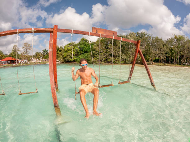 istock Young man having fun on swing in a beautiful lagoon on a sunny day 1370518969