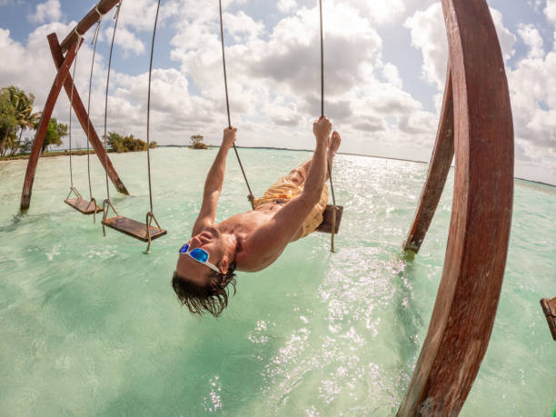 istock Young man having fun on swing in a beautiful lagoon on a sunny day 1370519009