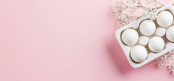 istock Easter concept. White eggs in ceramic holder and flowers on pink background 1370519043