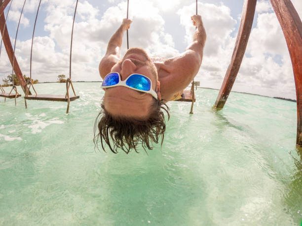 istock Young man having fun on swing in a beautiful lagoon on a sunny day 1370519056