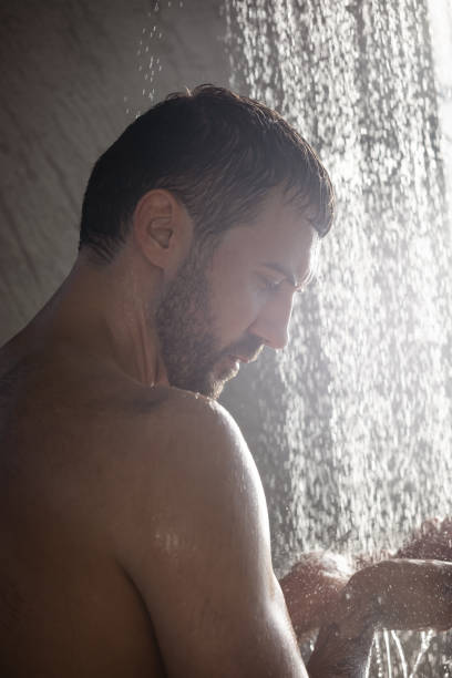 istock Handsome young man taking shower standing under falling water drops, washing body and head in modern bathroom at home. Selfcare and wellness 1370519281