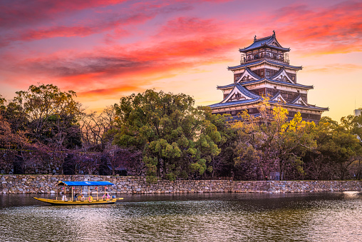 24 march 2019, Hiroshima - Japan: Hiroshima Castle with a boat with tourists in front at sunset