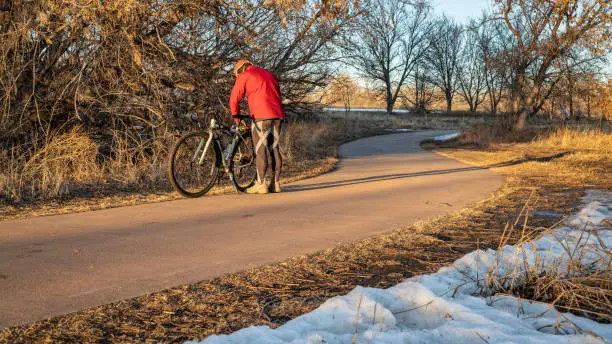 senior male cyclist with his touring bike on a biking trail along Poudre River in Fort Collins, Colorado, sunset winter scenery