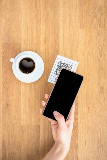 istock Top view Hand's customer scan QR code for online menu service at table in restaurant. New contactless technology lifestyle protection coronavirus pandemic in restaurant. Flat lay, wooden table 1370523368