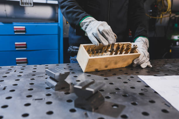 Worker hands with protective gloves holding a box with drill bits stock photo