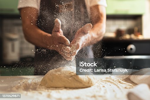 istock Chef's hands spraying flour over the dough 1370529871