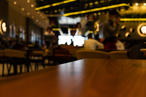 Wooden board empty table in front of blurred restaurant background. Perspective brown wood over blur in restaurant can be used for display or montage your products