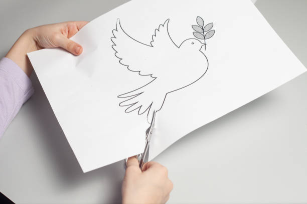 istock Children's hands are carving a crane on a white paper with small scissors 1370532839