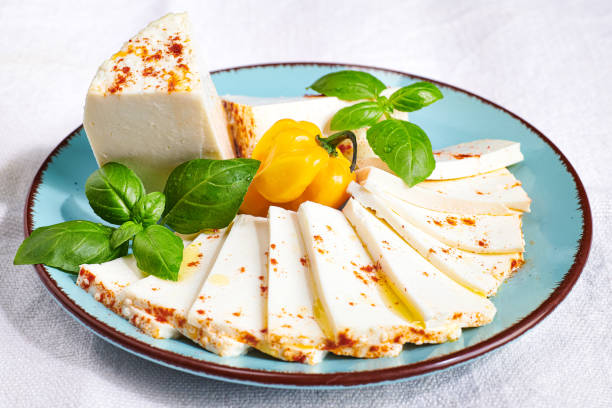 cheese platter on white table cloth background. plate of fresh soft cheese garnished with basil and chillies. - farmers cheese imagens e fotografias de stock