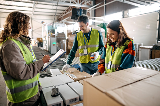 Portrait of warehouse colleagues preparing packages for shipping during daytime