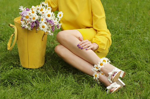 A girl is resting on the grass in summer with a bouquet of daisies in her bag.