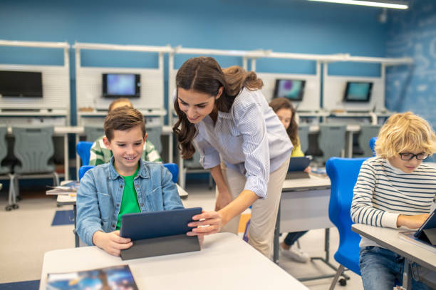 istock Woman leaning over looking into boys tablet 1370537084