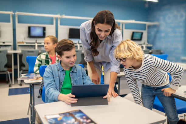 istock Woman and two students looking at tablet 1370537102