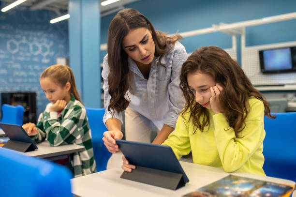 istock Teacher bent over thinking girl with tablet 1370537119
