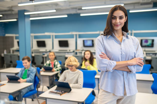 istock Woman confidently looking at camera and students sitting behind 1370537120