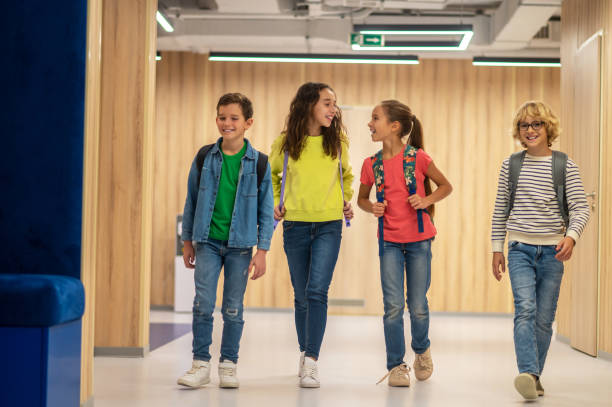 istock Joyful children with backpacks walking along corridor 1370537208
