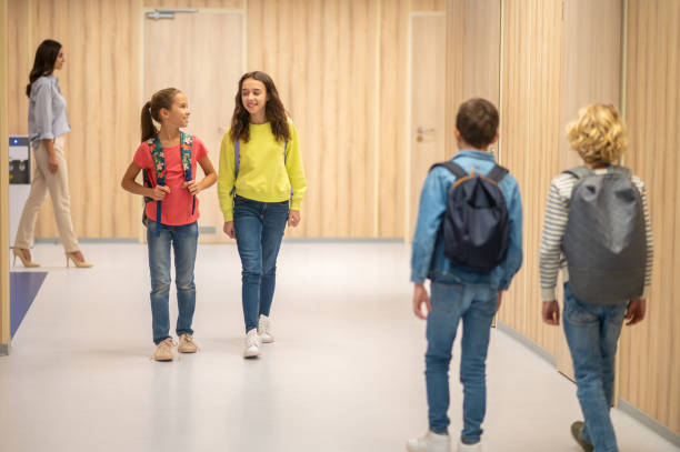 istock Girls walking hallway and boys with backs to camera 1370537212