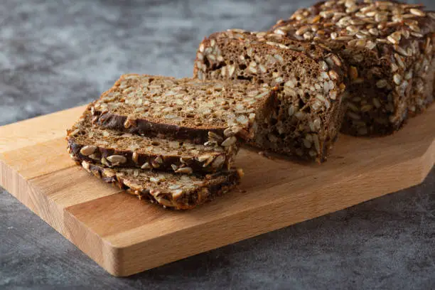 Sliced rye bread on cutting board. Whole grain rye bread with seeds.