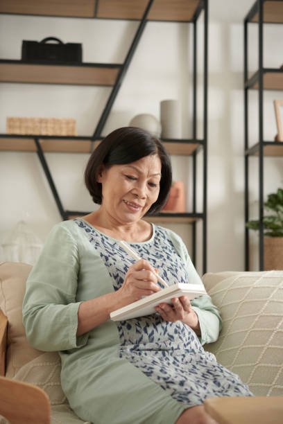 istock Senior Woman Writing Memories in Diary 1370540782