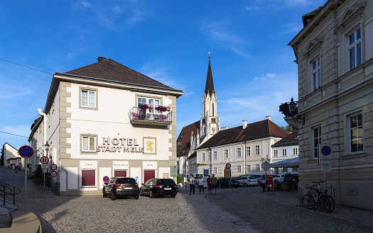 Melk, Austria, July 4, 2021: View of the center of this small town in Lower Austria. In the background is the Parish church of the Assumption (German: Stadtpfarrkirche Mariä Himmelfahrt). Melk is situated in the Danube Valley which is listed as UNESCO World Heritage Site.