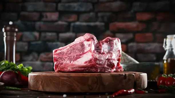 Raw pork steak placed on wooden cutting board. Preparation of meat, dark background.