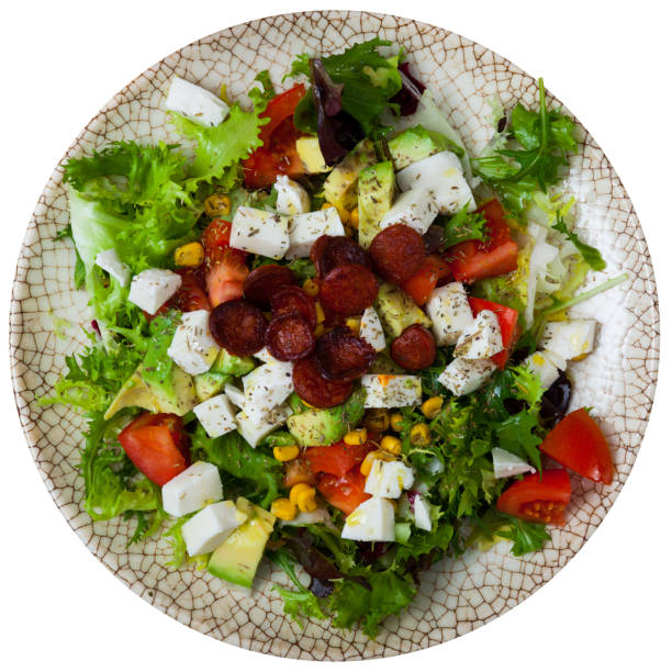 Delicious salad with vegetables, mozzarella and roasted sliced sausages. Isolated over white background