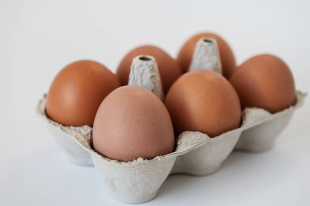 istock Closeup of fresh brown eggs in paper box over white background 1370547779