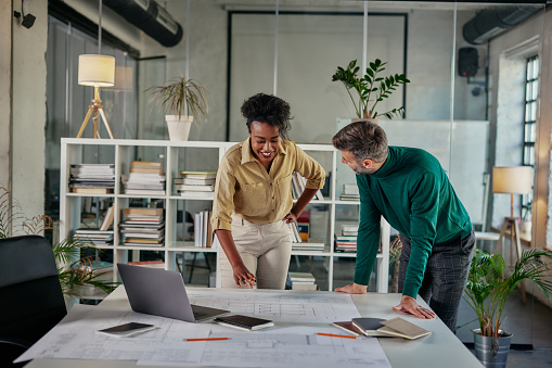 Two young multiracial business couple having a successful meeting in modern office. They are standing at the worktable and going through paperwork