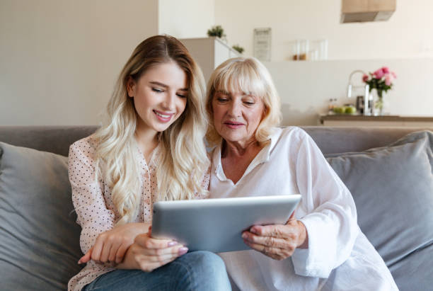istock Happy smiling girl using tablet computer with her grandmother 1370549509