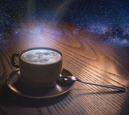 a cup of coffee with the moon and clouds on the background of the night sky. copyspace. The concept of inspiration and creativity.