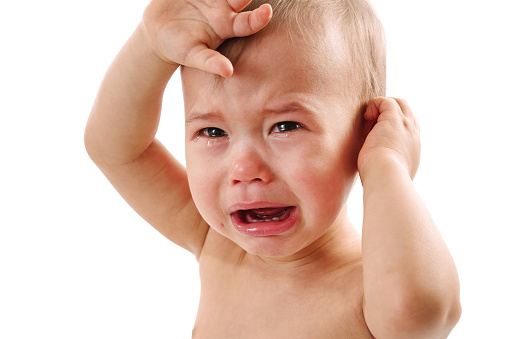 Closeup shot of an adorable upset little  baby boy crying on white background.
