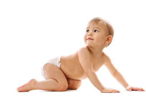 Adorable curious little boy in diaper is crawling and looking back on white background.