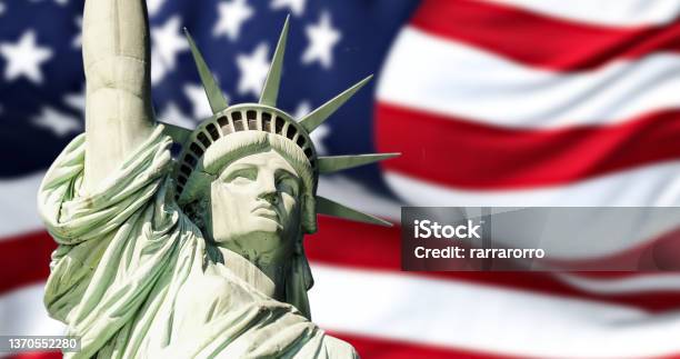 The Statue Of Liberty With Blurred American Flag Waving In The Background Stock Photo - Download Image Now