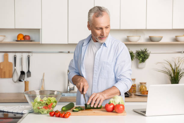 istock Handsome man standing at the kitchen using laptop and cooking 1370554282
