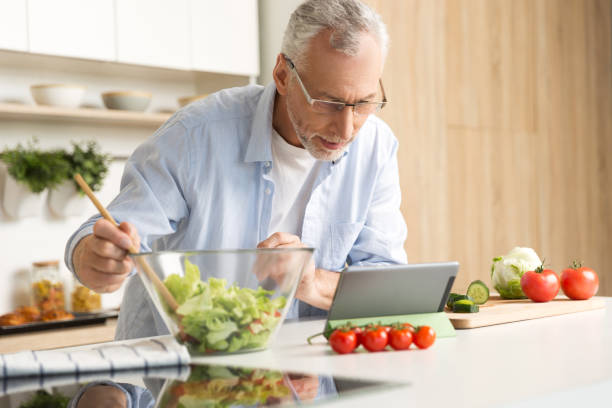 istock Concentrated mature man cooking salad using tablet 1370554572