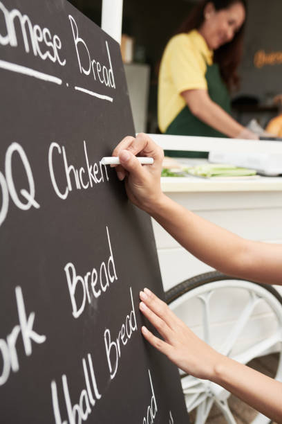 istock Vendor Writing List of Dishes on Board 1370554616