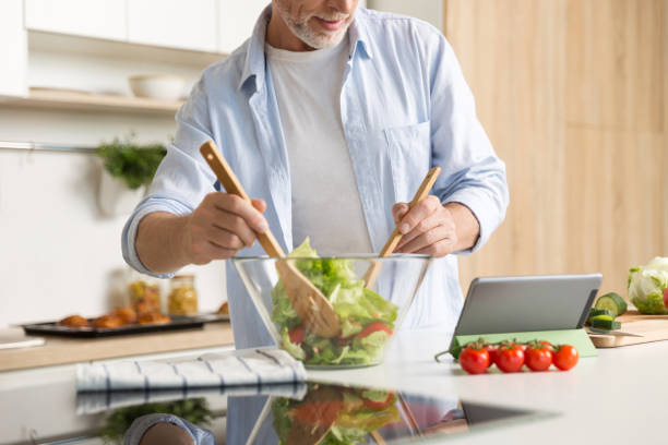 istock Cropped image of mature man cooking salad using tablet 1370555496