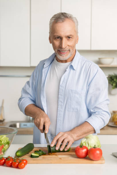 istock Mature attractive man standing at the kitchen cooking 1370555757