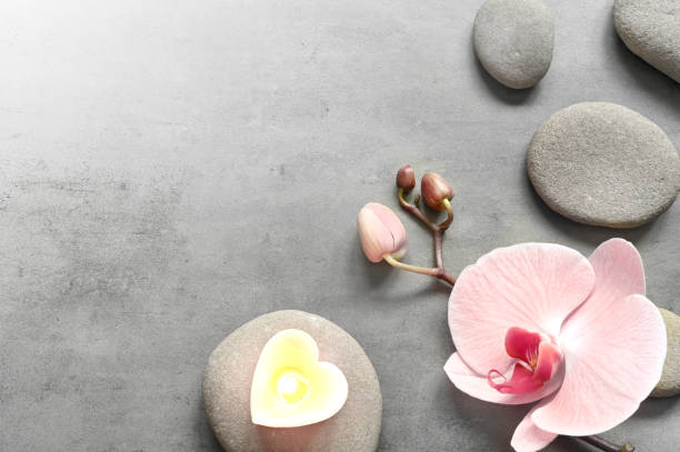 istock Flat lay composition with spa stones, orchid pink flower and heart on grey background. 1370556654