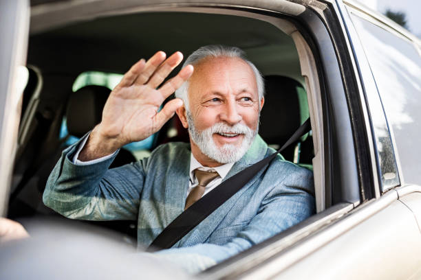 istock Senior man driving waving from car 1370559762