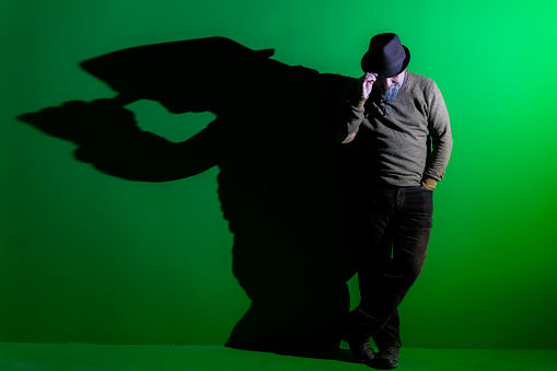 yeşil arka planlı stüdyoda yapay ışık önünde poz veren adam