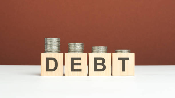 istock debt text on wooden blocks with coins on brown background 1370560206
