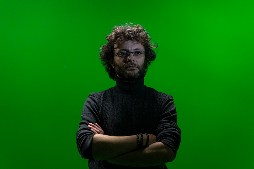 Stüdyoda çekilmiş kıvırcık saçlı adam portresi. Yeşil arka plan önünde yapay ışıkla fotoğraflnamıştır. full frame makine ile çekilmiştir.