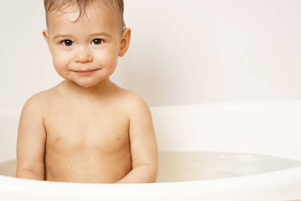 Smiling child enjoys bath time, showcasing a moment of joy and innocence with bath toys.