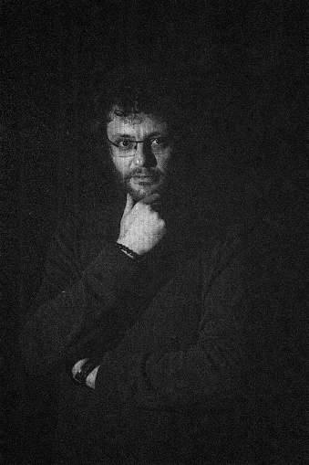 Stüdyoda çekilmiş kıvırcık saçlı adam portresi. Siyah beyaz ve yüksek ISO değerinde çekilen grenli fotoğraf. full frame makine ile çekilmiştir.