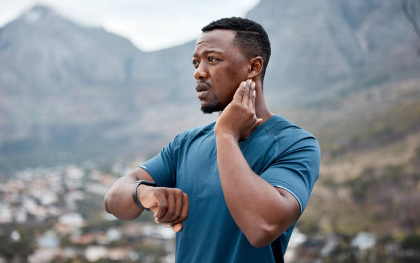 shot of a sporty young man checking his pulse while exercising outdoors - ouvir o batimento cardíaco imagens e fotografias de stock