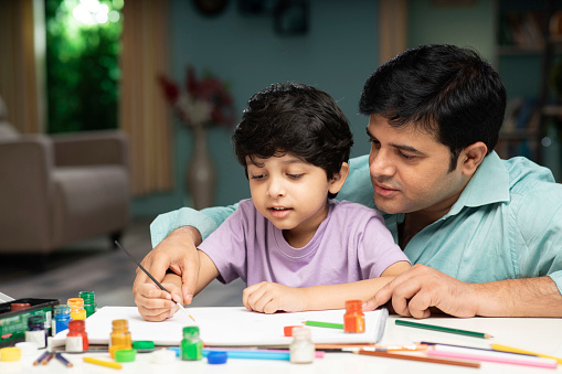 Father and son painting together at home.