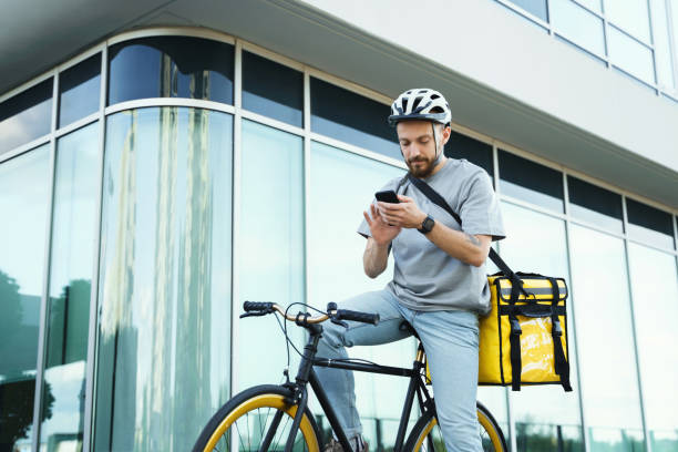 istock Express delivery courier with insulated bag looking at phone on bicycle. 1370567146