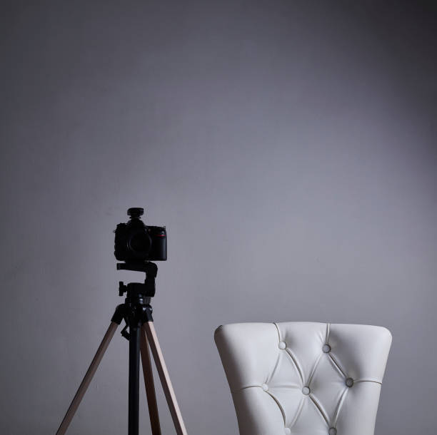 istock Camera on a tripod with white antique armchair 1370567520